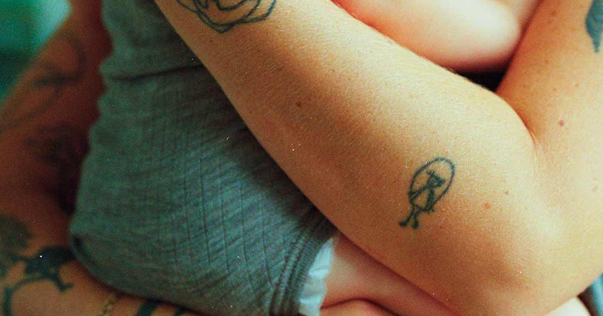 Mor holder baby i bodystocking i favnen